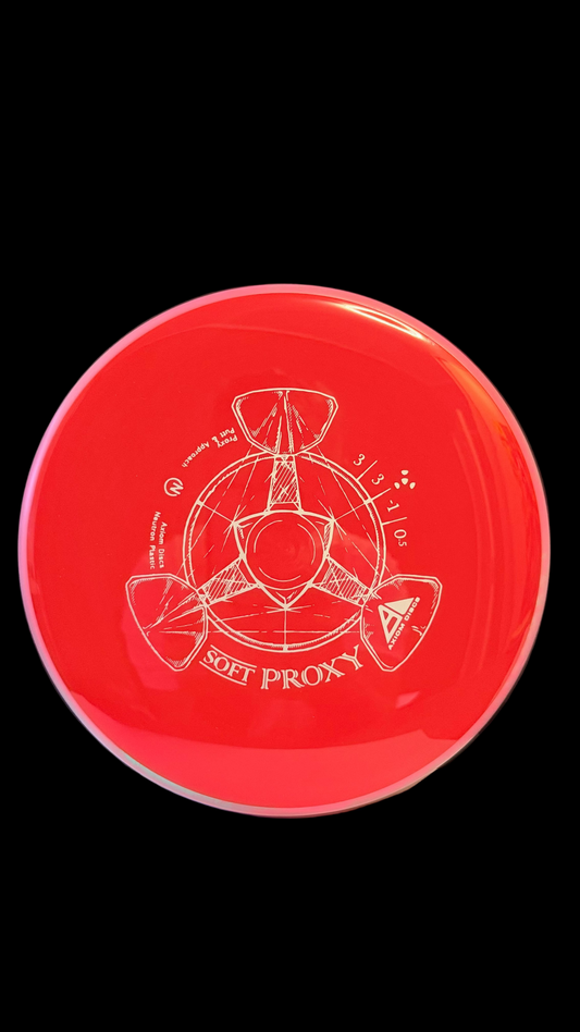Red Axiom Soft Proxy disc golf putter with a pink rim and white line-art stamp displayed on a white surface.